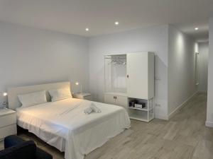 a white bedroom with a bed and a cabinet at Apartamentos Barcelona - Iberia in Barcelona