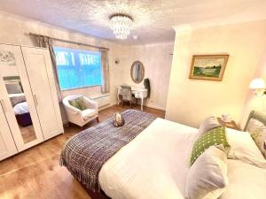 a bedroom with a bed and a chair and a window at Passford House Hotel in Lymington