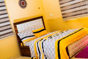a bedroom with a bed in a yellow room at Linea Recta 3C in Abuja