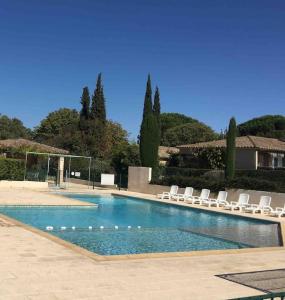 una piscina con sillones blancos y una pelota de voleibol en Mazet de Malo en Saint-Rémy-de-Provence