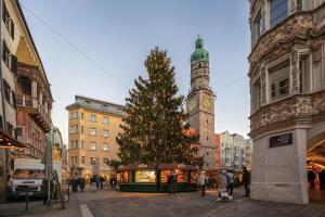 Un arbre de Noël dans une ville avec une tour d'horloge dans l'établissement Kaiser Max Design Appartements, à Innsbruck