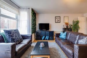 a living room with leather couches and a tv at Cosy 2BR Modern Apt with Free Parking in Liverpool