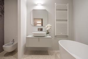 a white bathroom with a sink and a tub at Ninfea Luxury Suites in Venice