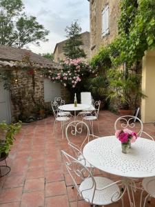 a patio with white tables and chairs and flowers at La Maison de Mama C: Charming french village home in Sainte-Colombe-sur-lʼHers