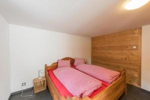 a bedroom with a wooden bed with pink pillows at Birkenhof 4-Bett in Flühli