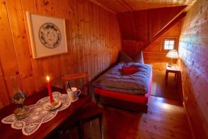 um pequeno quarto com uma cama e uma mesa com uma vela em Ferienhaus Fromsenrüti em Walzenhausen