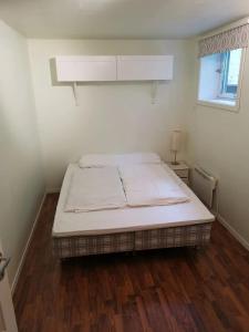 a bed in a white room with a wooden floor at Big, spacious apartment with free parking in Tromsø +5 photos