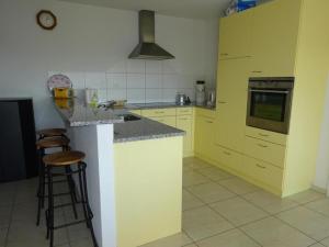 a kitchen with yellow cabinets and a counter with stools at Rehalp Westen in Bischofszell