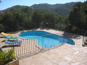 a swimming pool with two chairs and a fence at La gervaise in Begur