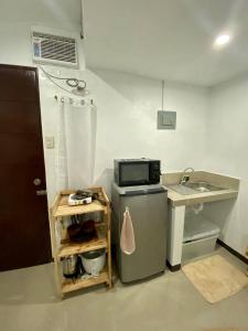 a small kitchen with a sink and a microwave at The Tiny Room Apartment Units near Anonas and Cubao in Manila