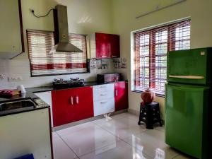 eine Küche mit roten Schränken und einem grünen Kühlschrank in der Unterkunft Maliyakal Homestay in Ernakulam