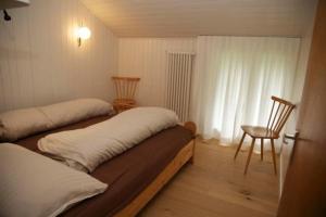 um quarto com duas camas e uma cadeira e uma janela em Ferienhaus Befang 17 em Wildhaus