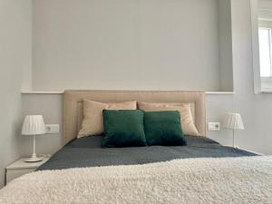 1 dormitorio con 1 cama con 2 almohadas verdes en ÁTICO VALDELAGRANA PLAYA - Aire Acondicionado y Piscina, en El Puerto de Santa María