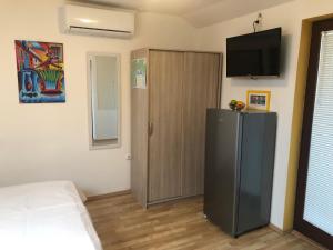 a bedroom with a refrigerator and a television on the wall at Studio Neven with Sea View in Baška