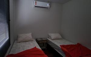 two twin beds in a room with a window at 300m-da Av das Cataratas- Ar Condicionado - Estacionamento Privado in Foz do Iguaçu