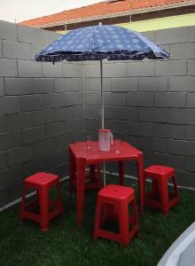a red table with two red stools and an umbrella at 300m-da Av das Cataratas- Ar Condicionado - Estacionamento Privado in Foz do Iguaçu +6 photos