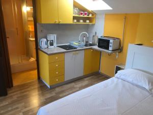 a small kitchen with yellow cabinets and a microwave at Studio Neven with Sea View in Baška