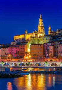 a view of a city at night with a bridge at Hotel Parisien in Menton