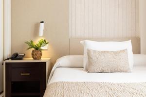 Hotel Plaza Del Castillo في مالقة: غرفة نوم مع سرير مع وسادة وطاولة