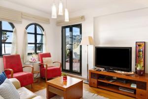 uma sala de estar com televisão e cadeiras vermelhas em Luzias Apartment em Funchal