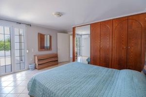 a bedroom with a blue bed and a wooden cabinet at Lefkathia Beach Villa - Gated Beach-Front Private Villa at Lefkathia Beach, Chios! in Volissos