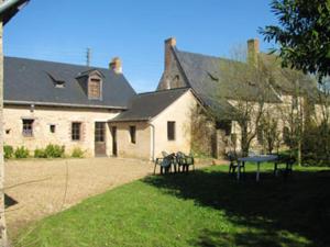 a house with two picnic tables in front of it at Maison spacieuse avec jardin à Morannes sur Sarthe in Saint-Germain