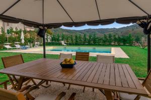einen Holztisch mit einer Schale Obst und einem Sonnenschirm in der Unterkunft Villa Cristina modern farmhouse with Private Pool in Monsagrati