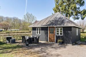 a small black shed with a table and a patio at First Camp Bøsøre Strand Feriepark in Hesselager