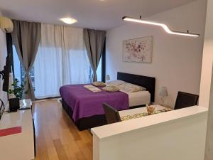 a bedroom with a bed with purple sheets and a window at Nova Galerija West App Dora in Zagreb