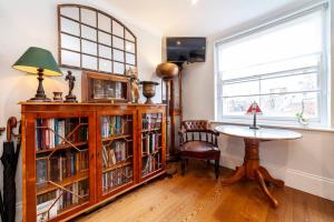 une chambre avec une table et une étagère avec des livres dans l'établissement Outstanding Antique 1BR flat in Soho, à Londres