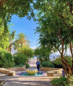 a person walking through a park with a fountain at Sablettes Beach-plage-vue mer-centre ville in Menton