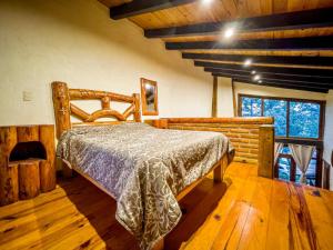 ein Schlafzimmer mit einem Bett in einem Zimmer mit Holzböden in der Unterkunft DNellys/Pinguica 1 in Mazamitla