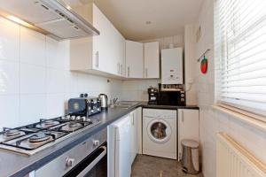 a kitchen with a stove and a washing machine at Calabria 3 - Spacious apartment in London