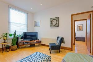 ein Wohnzimmer mit einem TV und einem Stuhl in der Unterkunft Calabria 3 - Spacious apartment in London