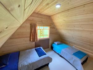 2 camas en una cabaña de madera con ventana en Cabaña campestre en Chiquinquirá, en Saboyá