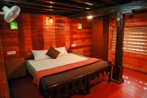 a bedroom with a bed in a room with wooden walls at Keloth Tharavadu in Panamaram