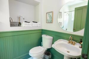 a green and white bathroom with a toilet and a sink at Suite 9 Historic Art City Inn in Springville