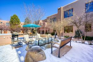 a patio with benches and an umbrella in the snow at El Corazon #30 in Santa Fe