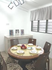 einen Esstisch mit Stühlen und einen Tisch mit Obst darauf in der Unterkunft Sweet 3 bedroom home @ Canning Garden, Ipoh in Ipoh