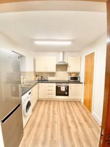 ダブリンにある2 bed Apartment in City Centreの白い家電製品が備わるウッドフロアのキッチン
