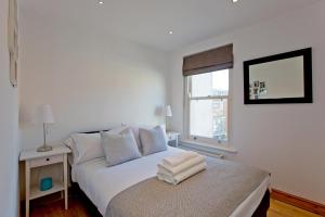 a white bedroom with a bed and a window at Convenient 1 bedroom apartment with parking in London