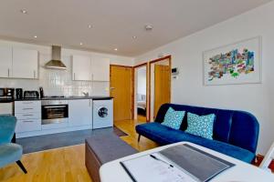 a living room with a blue couch and a kitchen at Convenient 1 bedroom apartment with parking in London