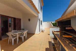 a patio with a table and chairs and an oven at G - Vila Céu Guesthouse in Odiáxere