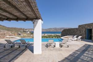 a group of chairs sitting on a patio next to a pool at Elegant Mykonos Villa Air Private Pool 4 Bedrooms Sea View Panormos in Mykonos