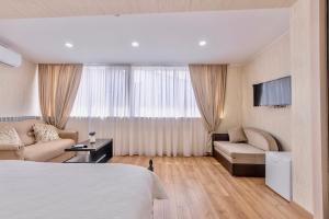 Una habitación de hotel con una cama, un sofá y un televisor. en Q&B Boutique House, en Tiflis