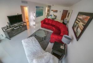 a living room with a red couch and a tv at Beautiful penthouse condo with stunning views of both ocean and city in Hollywood