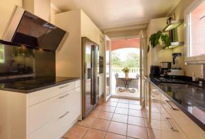 a kitchen with white cabinets and a tile floor at La Maisonnette du Clos in La Roquette-sur-Siagne