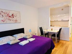 a bedroom with a purple bed with a table and chairs at Nova Galerija West App Dora in Zagreb