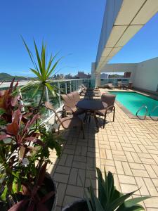 eine Terrasse mit einem Tisch und Stühlen sowie einem Pool in der Unterkunft Praia do Canto Apart Hotel in Vitória
