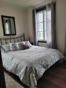 1 dormitorio con cama, espejo y ventana en Om Villégiature, en Saint-Laurent-de-l'ile d'Orleans